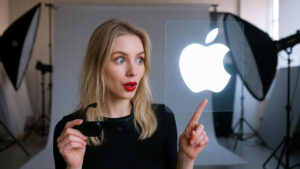 Une femme tenant une paire de lunettes intelligentes, elle pointe du doigt le logo d'Apple dans un studio photo